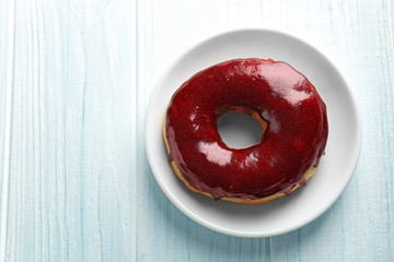 Wall Mural - Plate with tasty glazed donut on wooden background