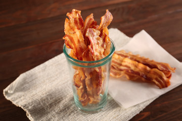 Wall Mural - Tasty bacon slices in glass cup on table