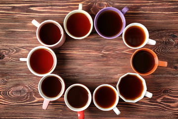 Poster - Delicious tea in cups forming circle on wooden background