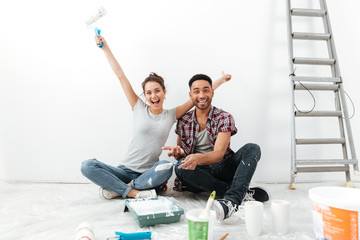 Wall Mural - Happy loving couple on floor in new flat makes repair.