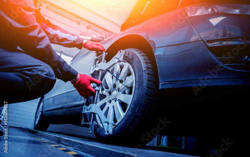 Fotografía Car mechanic installing sensor during suspension adjustment.