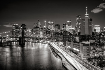 Fototapete - Lower Manhattan skyscrapers and Financial District. The Black & White elevated night view includes the West tower of the Brooklyn Bridge, East River and traffic light trails on the FDR Drive. New York