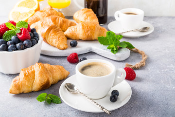 Healthy breakfast with coffee, croissants, fresh berries and orange juice on light gray background, selective focus, copy space.