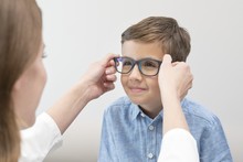 Female Optician Putting Glasses On Boy