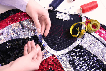 Female hands embroidering clothes by sequins on white background