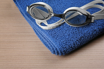 Wall Mural - Swimming goggles with towel on wooden background