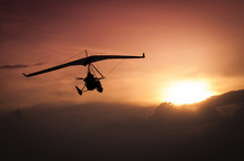 Weight-Shift Ultralight Aircraft Silhouette  In The Sunset, Above Stormy Clouds