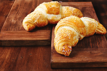 Close-up of two homemade sesame croissants on wooden table. 