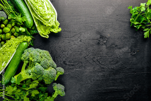 Stampe Collection of fresh green vegetables placed on black stone