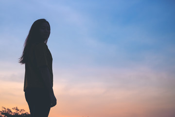 Silhouettes of a standing woman with the sky before sunset  background and copy space