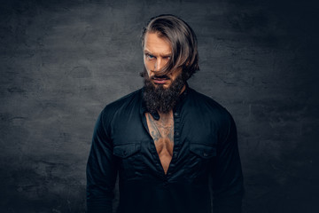 Canvas Print - A man with long hair and tattoos on his chest dressed in a black shirt.