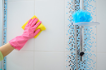 Wall Mural - A woman washer is cleaning tiled surface in kitchen. The girl in pink gloves