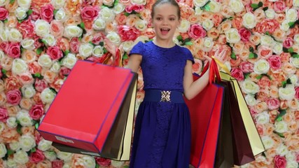 Wall Mural - Childrens shopping. Portrait of happy little girl in dress, background of bright floral wall