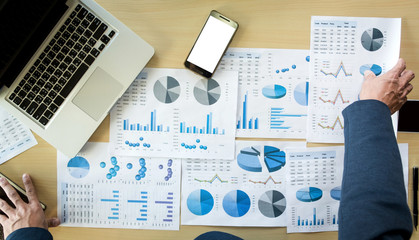 Wall Mural - businessman hands working with computer and smart phone with business graph on desk as concept.