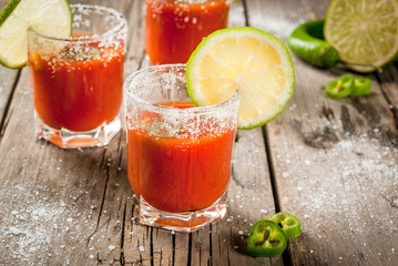 Wall Mural - Mexican traditional alcohol drink. Sangrita, with tequila, tomato juice, hot spices, chili and lime.Analogous bloody mary. On rustic wooden table, copy space