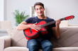 © Elnur - Young man practicing playing guitar at home