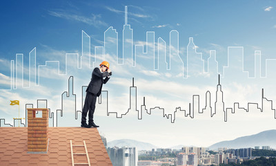 Engineer man standing on roof and looking in binoculars. Mixed m