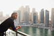 © phocal Media - Expat man leaning at balcony.