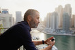 © phocal Media - Expat man using mobile at balcony.