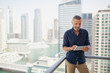 © phocal Media - Expat man using digital tablet at balcony.