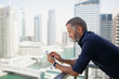 © phocal Media - Expat man messaging on mobile at balcony.