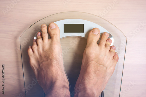 Male Feet Standing On Electronic Scales For Weight Control Male Feet Standing On Electronic Scales For Weight Control