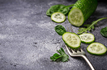 Wall Mural - Sliced cucumber on fork and spinach leaves.