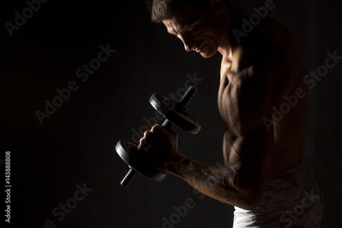 Zdjęcie XXL muskularny mężczyzna trzyma wagę na ciemnym tle
