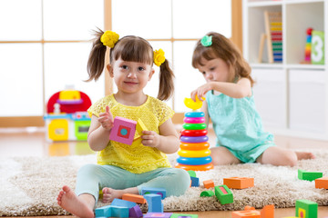 Poster - Kids playing with blocks together. Educational toys for preschool and kindergarten child. Little girls build toys at home or daycare.