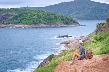 Wall Mural - Tourism and photography. Young traveling woman with camera and rucksack enjoying sea view on Phuket, Thailand.