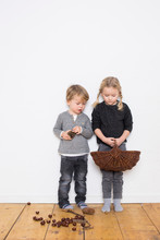 Young Girl And Boy, Girl Holding Wicker Basket, Boy Holding Pine Cone, Pine Cones And Conkers On Floor