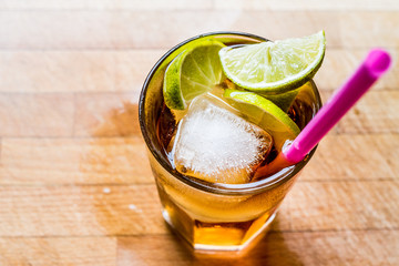 Wall Mural - Long island iced tea cocktail with lime, ice and served with pink straw.