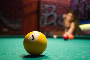 Wall Mural - A girl is playing billiards in a dark billiard club.