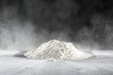 Wall Mural - Pile of flour on table against dark background