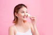 © makistock - Young lady applying blusher on her face with powder puff, skin care concept on pink background.