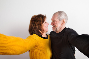 Wall Mural - Senior couple in love hugging, taking selfie. Studio shot.