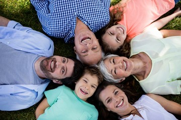 Multi generation family lying in park in a circle