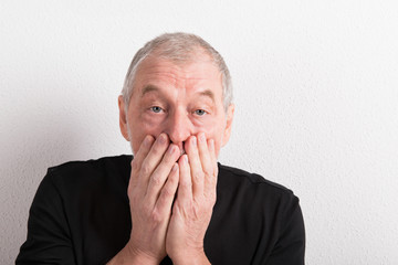 Wall Mural - Upset senior man with headache, holding his mouth, studio shot.