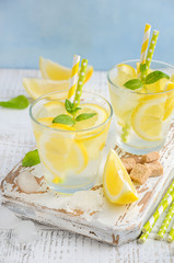 Cold refreshing summer drink with lemon and mint on wooden background.