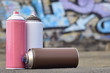 A still-life of several used paint cans of different colors against the graffiti wall