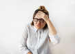 © shurkin_son - Stress at work concept. Portrait of funny young female office worker in striped shirt and glasses having headache holding her hand to the head. Beautiful young female feeling sick and strong migraine