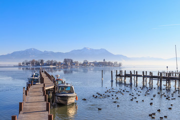 Boats at Jetty in Gstadt, Bavaria, Germany, with Lake Fraueninsel in the background on a cold winter day