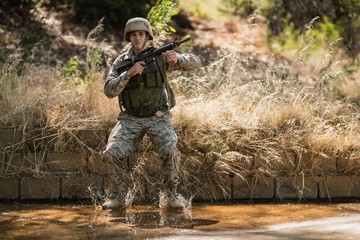 Military soldier with rifle jumping in water