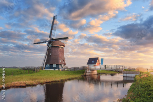 Foto Windmill near the water canal at sunrise in Netherlands
