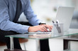 © Danuta - Young business man working on a laptop at his desk in the office, in view of the profile against the window