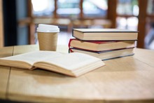 Books And Disposable Coffee Cup On Table In Cafe