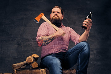 Wall Mural - Bearded lumberjack male with tattoos on arms holds the axe and beer bottle