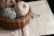 Ecru, brown and grey wool yarn with needles in wooden basket 