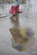 dziecko w kaloszach bawiące się w deszczu