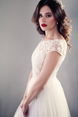 Wall Mural - Nice Bride in White Wedding Dress, Pretty Girl Fiancee with Curly Hair and Makeup on Background